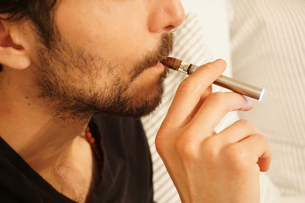 a young man smoking vape pen